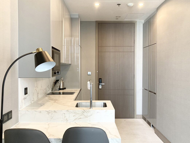 Project case image for The Esse Singha Complex apartment project in Thailand. The image features a sleek one-wall kitchen with modern cabinetry and a luxurious marble countertop. The design emphasizes clean lines, premium materials, and a minimalist aesthetic, creating a sophisticated and functional culinary space.