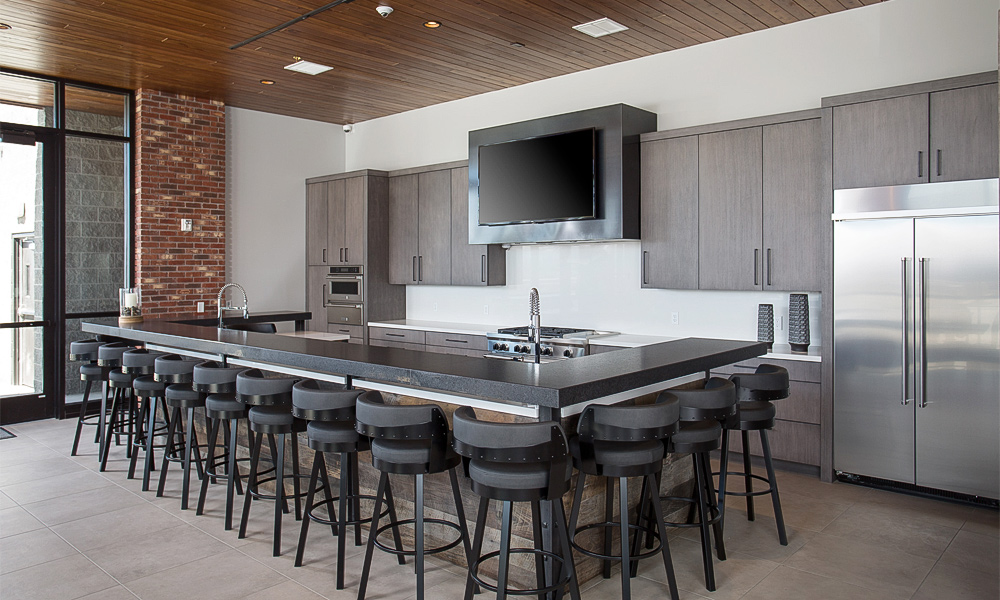 A close-up view of a one-wall kitchen with dark wood veneer cabinets and a central island. The rich, deep tones of the wood create a warm and sophisticated atmosphere, while the island provides additional workspace and a contemporary accent. The partial image showcases the elegant grain patterns and modern design elements.