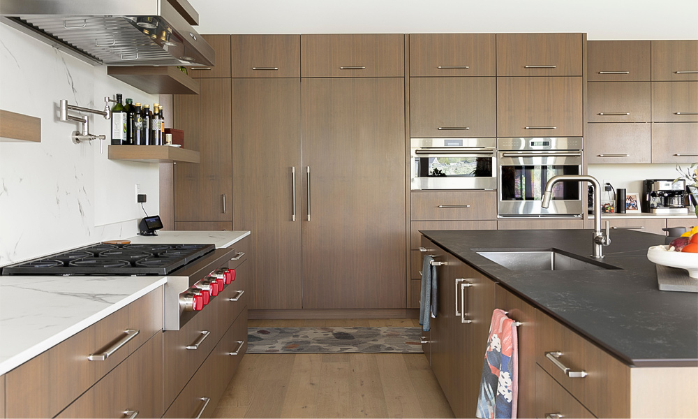 Close-up view of an L-shaped kitchen with wood veneer cabinets and a central island, highlighting the rich wood texture and modern design details.