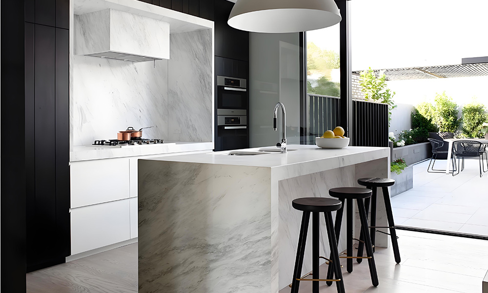 A one-wall kitchen with black and white lacquered cabinetry and a marble central island. The bold contrast between black and white creates a sophisticated modern look, while the marble island adds a touch of luxury and provides ample workspace.