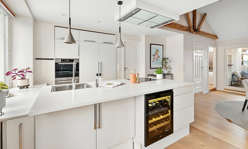 A modern one-wall kitchen featuring white cabinetry and a central island. The bright white cabinets create a clean, minimalist look, while the central island adds functionality and serves as a stylish focal point in the space.