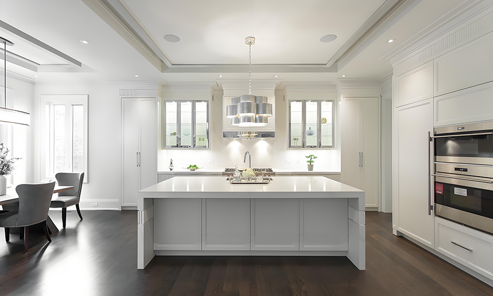 A stylish kitchen with high-gloss white cabinetry and a central island. The glossy finish of the cabinets reflects light, creating a bright, modern atmosphere, while the island provides both functional workspace and a contemporary focal point in the room.