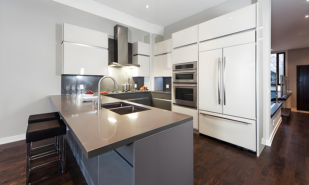 A side panoramic view of a modern kitchen with white cabinetry and a gray island. The contrast between the crisp white cabinets and the sleek gray island creates a balanced, contemporary look. The design emphasizes clean lines and a spacious, functional layout.