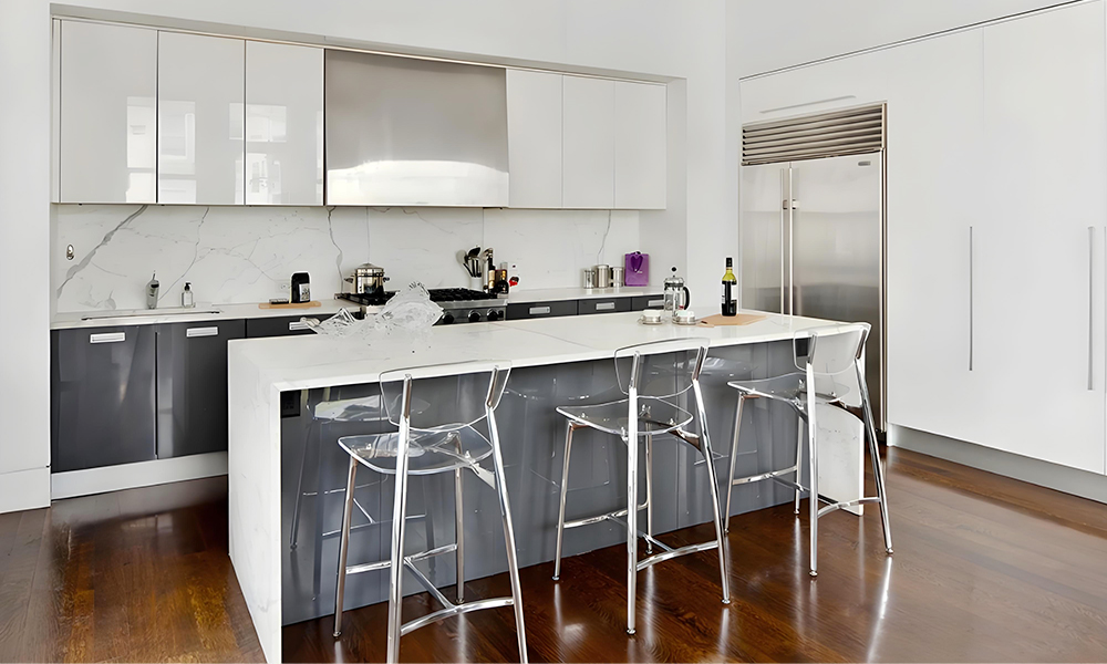 A modern kitchen with white cabinetry and a central island, creating a clean and bright space. The minimalist design highlights the crisp white tones, while the island adds both functionality and style to the layout.