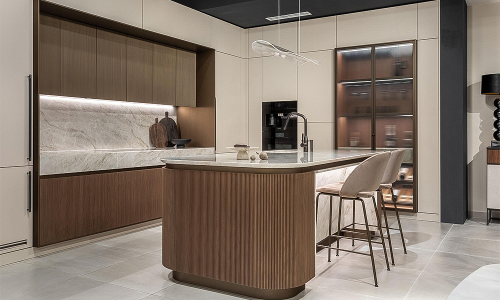 A modern kitchen featuring wood veneer cabinets with a sleek, minimalist design. The focal point is a large white marble island countertop, adding elegance and sophistication to the space. The kitchen has a clean and airy atmosphere, with soft lighting highlighting the natural textures of the materials.