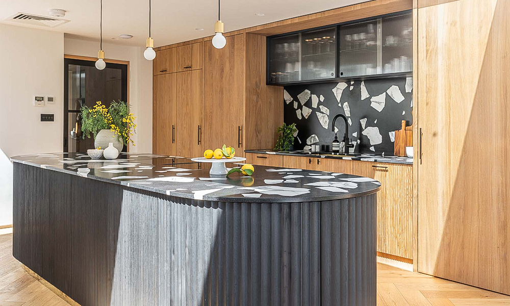 A kitchen featuring wood veneer cabinets paired with a black marble island countertop. The contrast between the warm wood tones and the sleek, dark marble creates a sophisticated and contemporary look, blending natural textures with modern elegance.