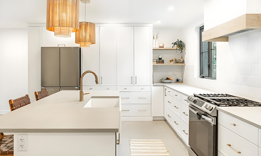 A modern kitchen with white lacquered cabinets in an L-shaped configuration, featuring a central island. The high-gloss white finish of the cabinetry gives the kitchen a sleek, contemporary look, while the central island serves as both a functional workspace and a gathering spot. The minimalist design with clean lines creates a spacious and open atmosphere, perfect for cooking and entertaining. The bright white surfaces reflect natural light, enhancing the overall airy, modern aesthetic of the kitchen.
