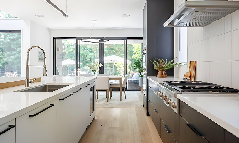 A close-up view of a modern one-wall kitchen featuring black and white lacquer cabinets. The design combines bold black lower cabinets with crisp white upper cabinets, creating a striking contrast. The central island, with its sleek, glossy surface, acts as both a functional prep area and a focal point in the space. The minimalist design highlights clean lines and smooth finishes, reflecting a contemporary aesthetic.