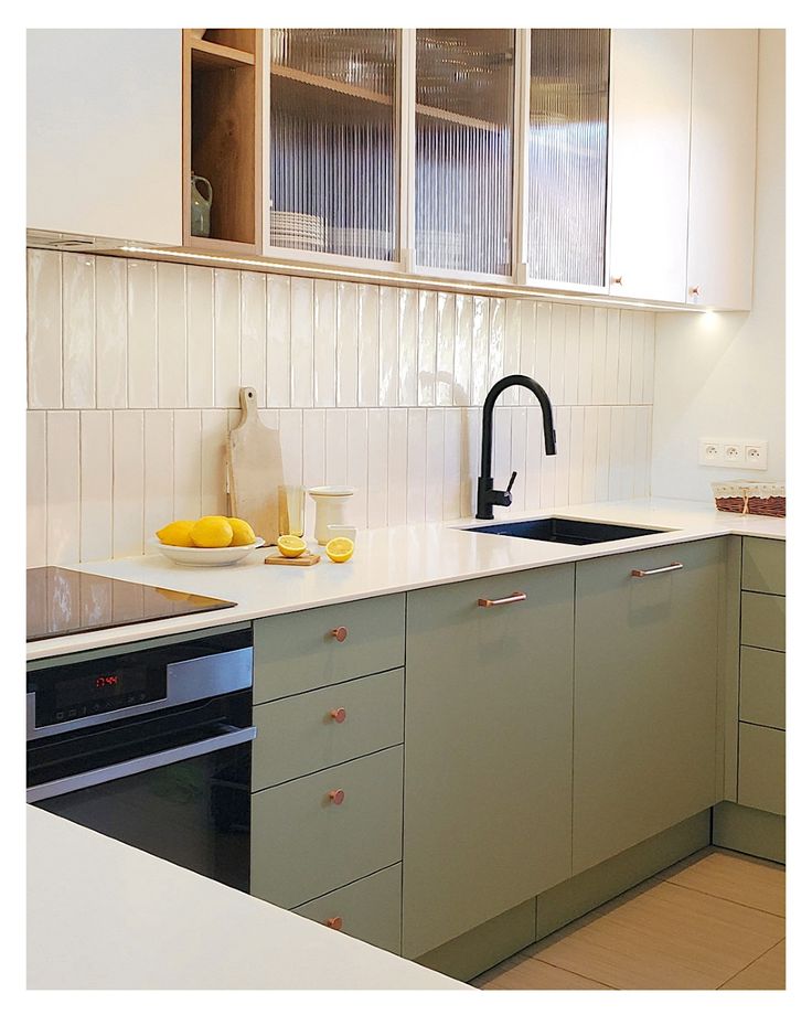 Green kitchen cabinets with walnut island, fluted panels, and warm pendants