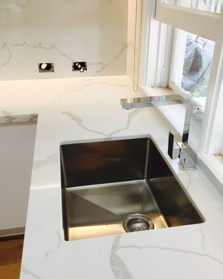 AIS Cabinet Large-format sintered stone cabinet countertops with a marble-like finish in a bright kitchen.